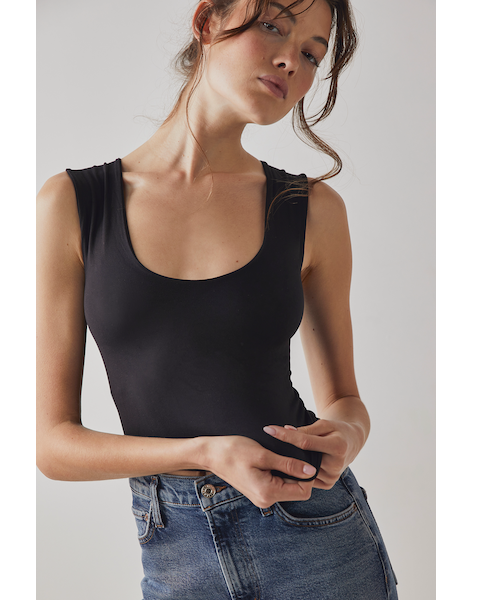 A female model wearing a black scoop-neck sleeveless tank top paired with a denim skirt.