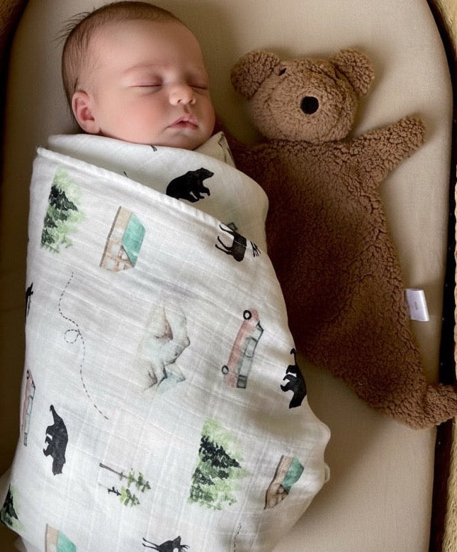 Newborn wrapped in an organic muslin adventure swaddle with teddy fleece comforter