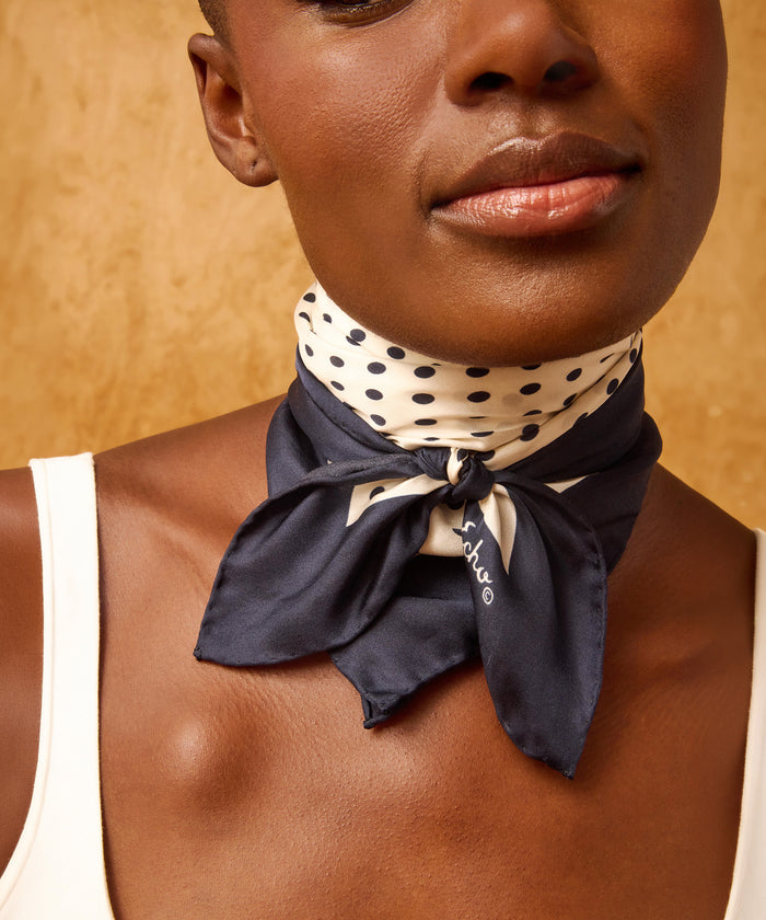 Navy blue square scarf with white polka dot pattern on a white background